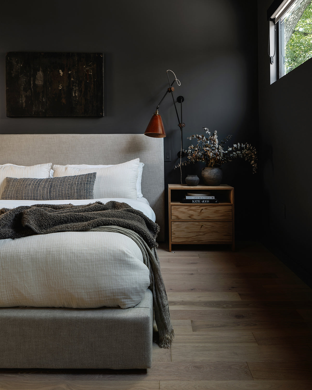 Large articulating black plug in wall sconce with tan handstitched cone leather shade in bedroom as bedside sconce