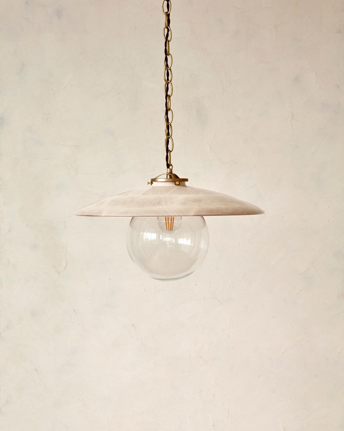 Large pendant light with oversized clear glass globe and decorative wooden clear maple shade with brass chain