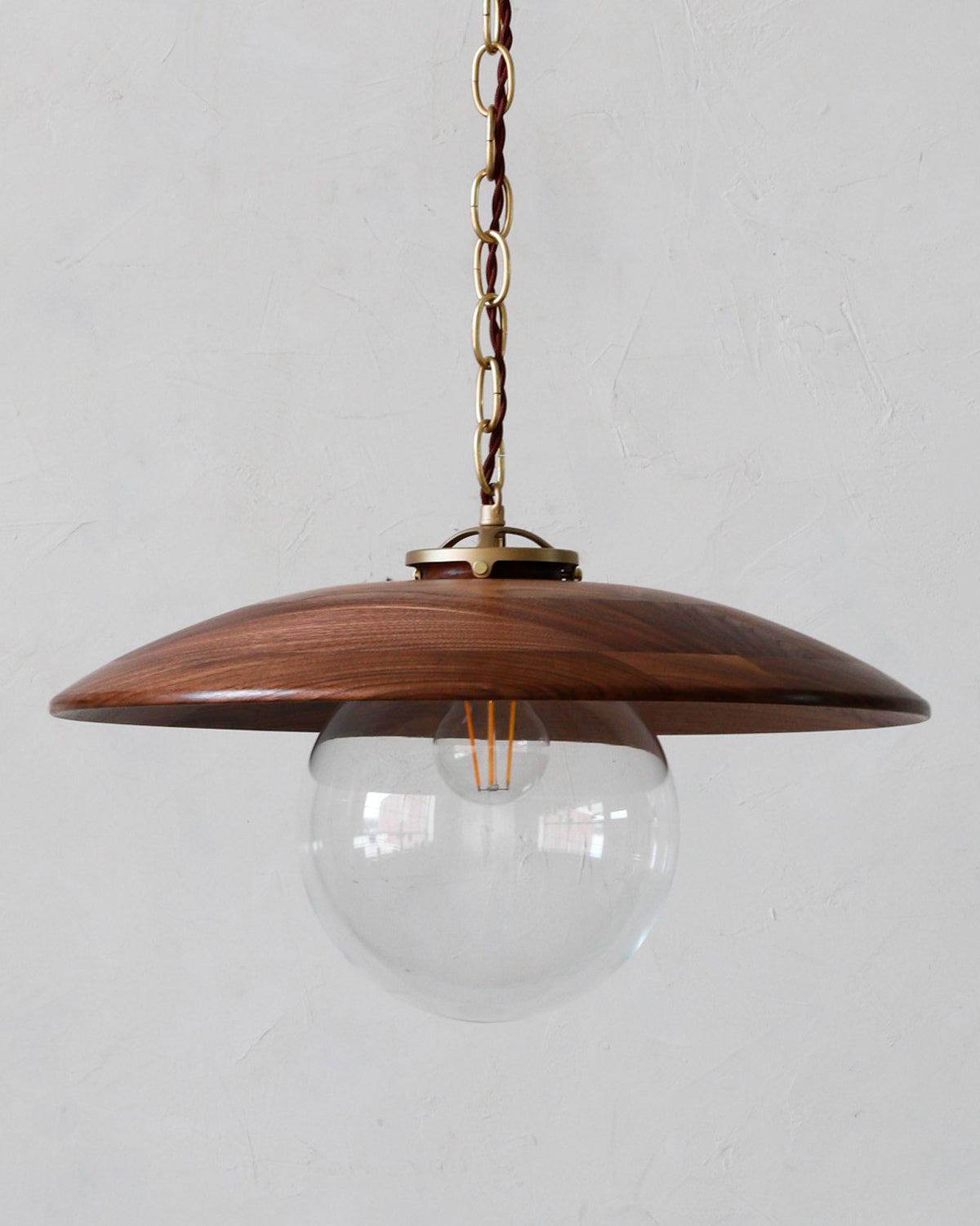 Large pendant light with oversized clear glass globe and decorative wooden black walnut shade with brass chain