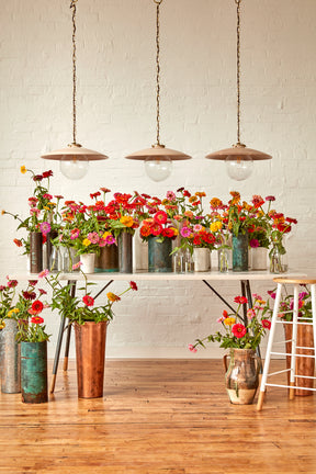 Large pendant lights with oversized clear glass globe and decorative wooden clear maple shade with brass chain hanging over table with floral arrangement