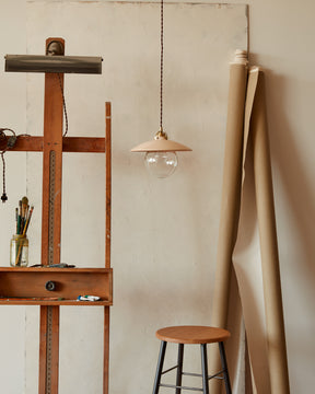 Pendant light with large clear glass globe and decorative wooden clear maple shade hanging in art studio. Made by Lostine in Philadelphia. Simple interior design, made in the USA. Warm American Modern Design