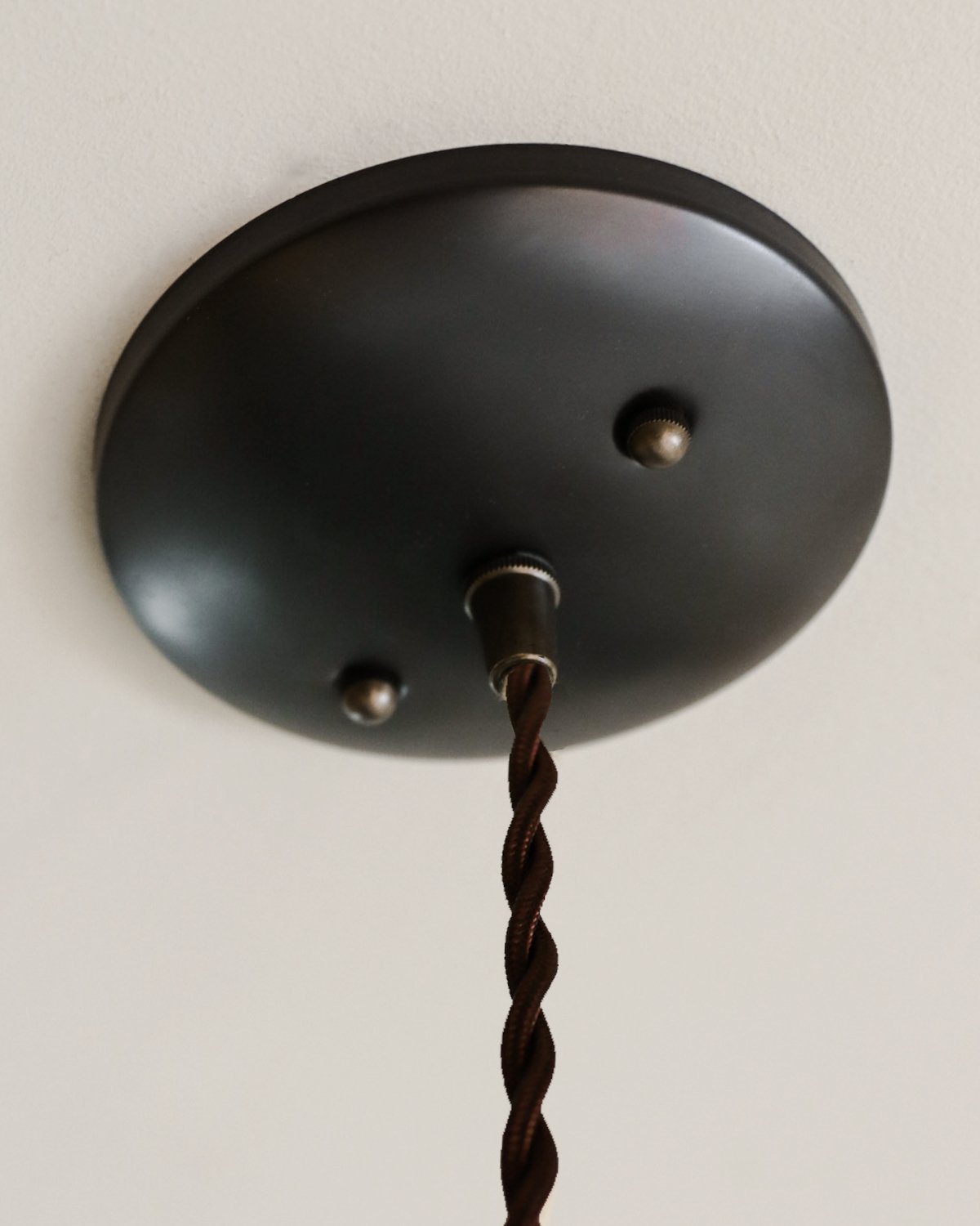 Black leather cone pendant with handstitched, perforated leather shade. Made by Lostine in Philadelphia. Hardwired or plug light fixture. Simple interior design, made in the USA.